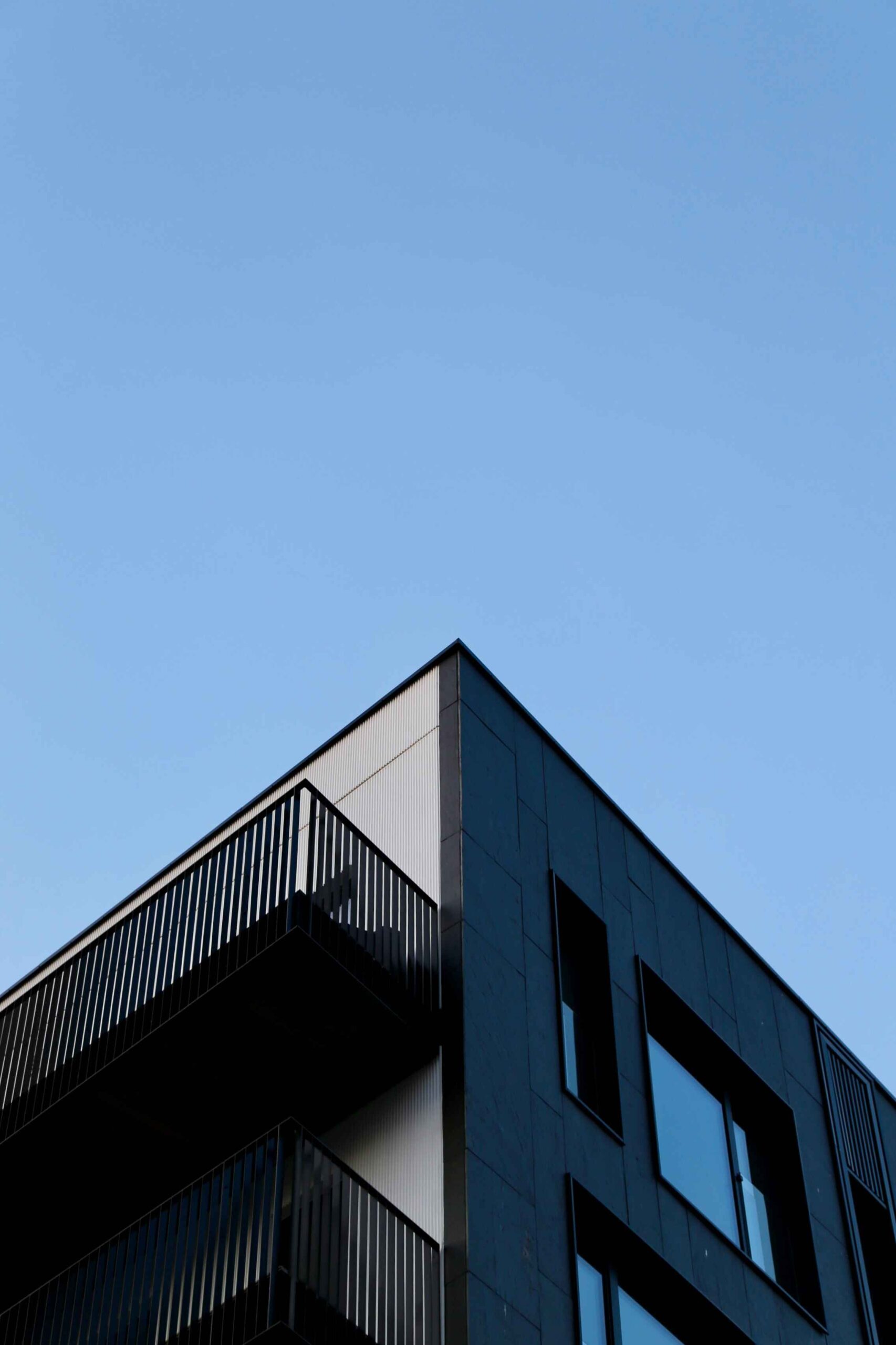 A grey building with balconies against a blue sky.
