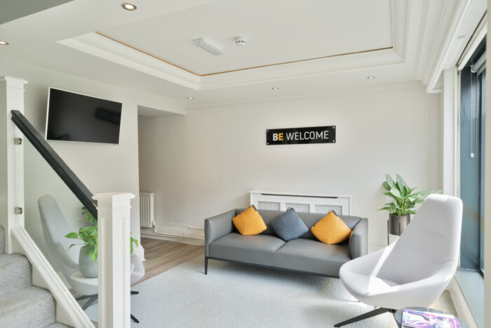 A white modern office space with a Be Welcome sign on the wall.