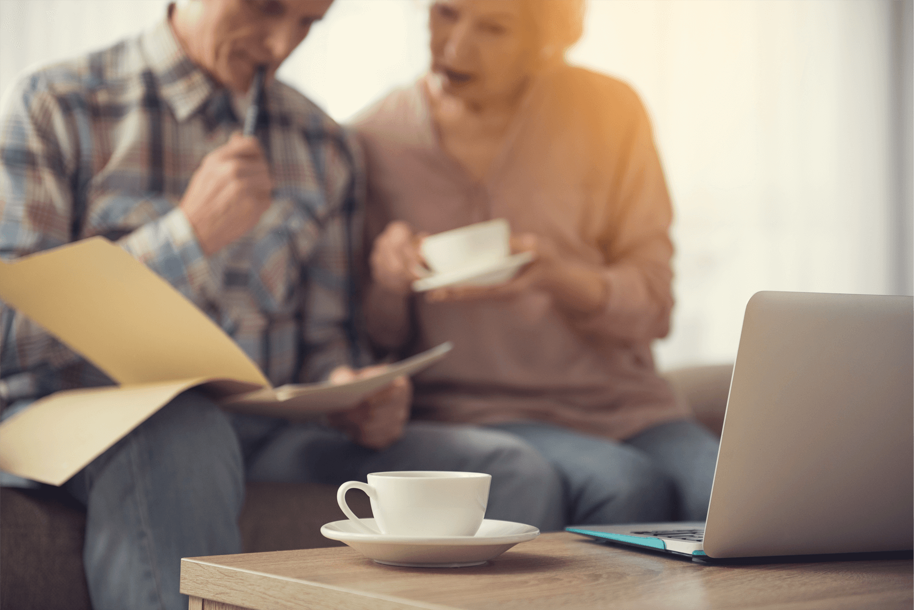 A couple sit reading documents whilst drinking coffee.