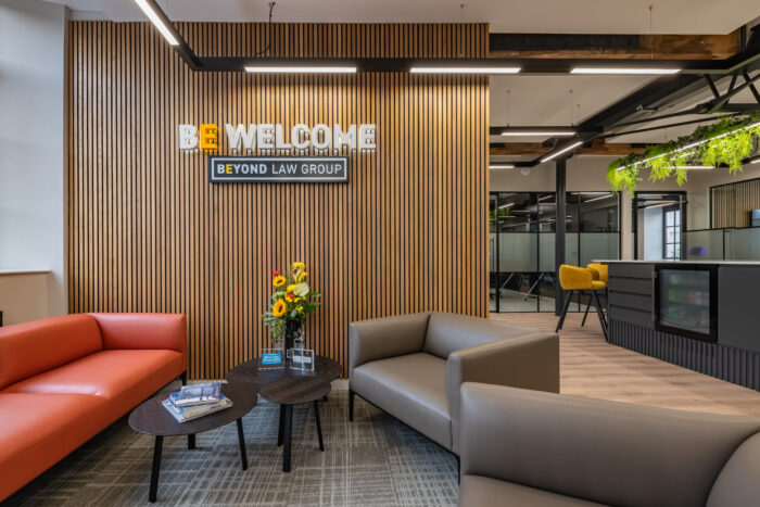 The Beyond Law Group office reception seating area with a sign reading Be Welcome with the Beyond Law Group logo below.