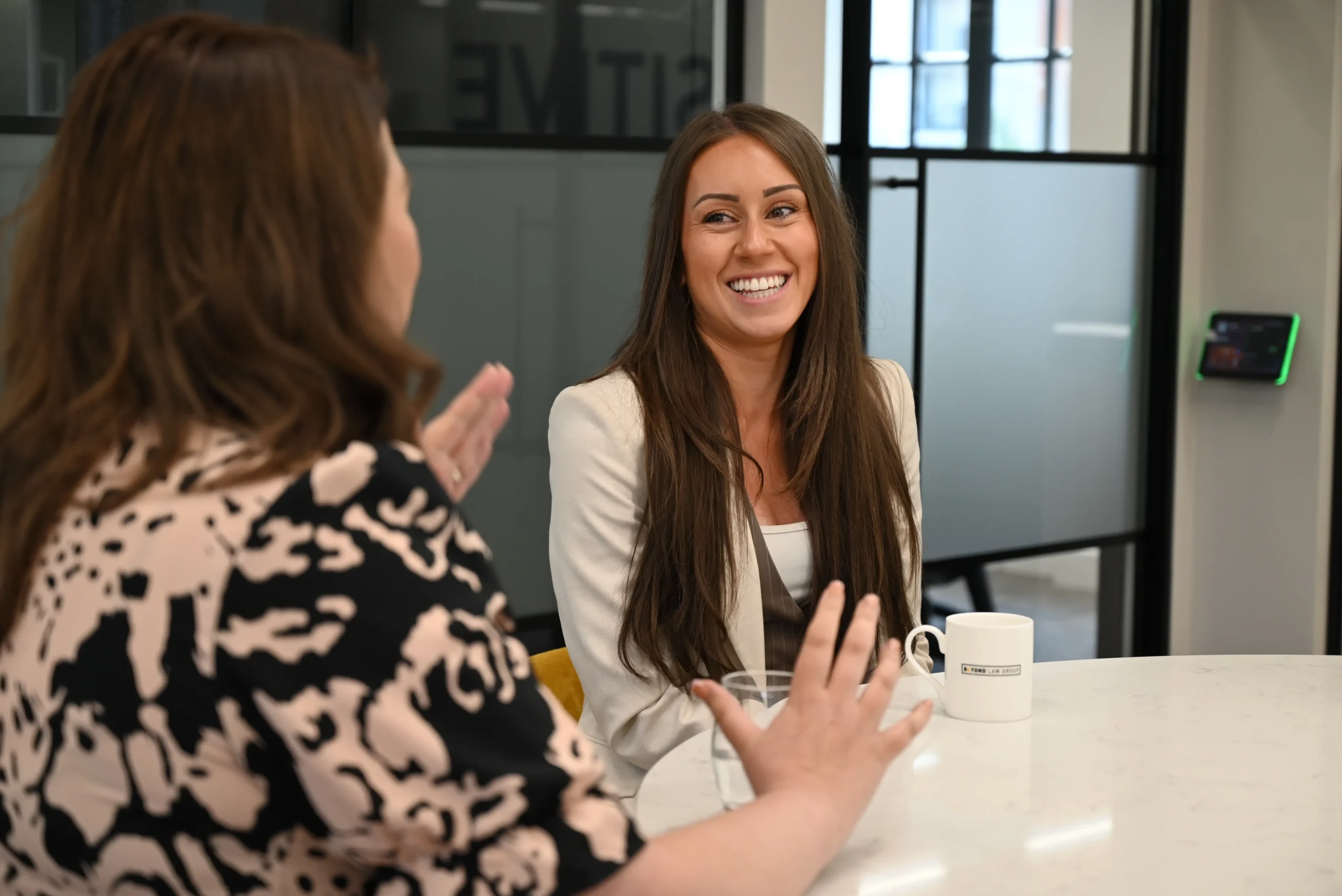 Two women sat at a table having a conversation and laughing.