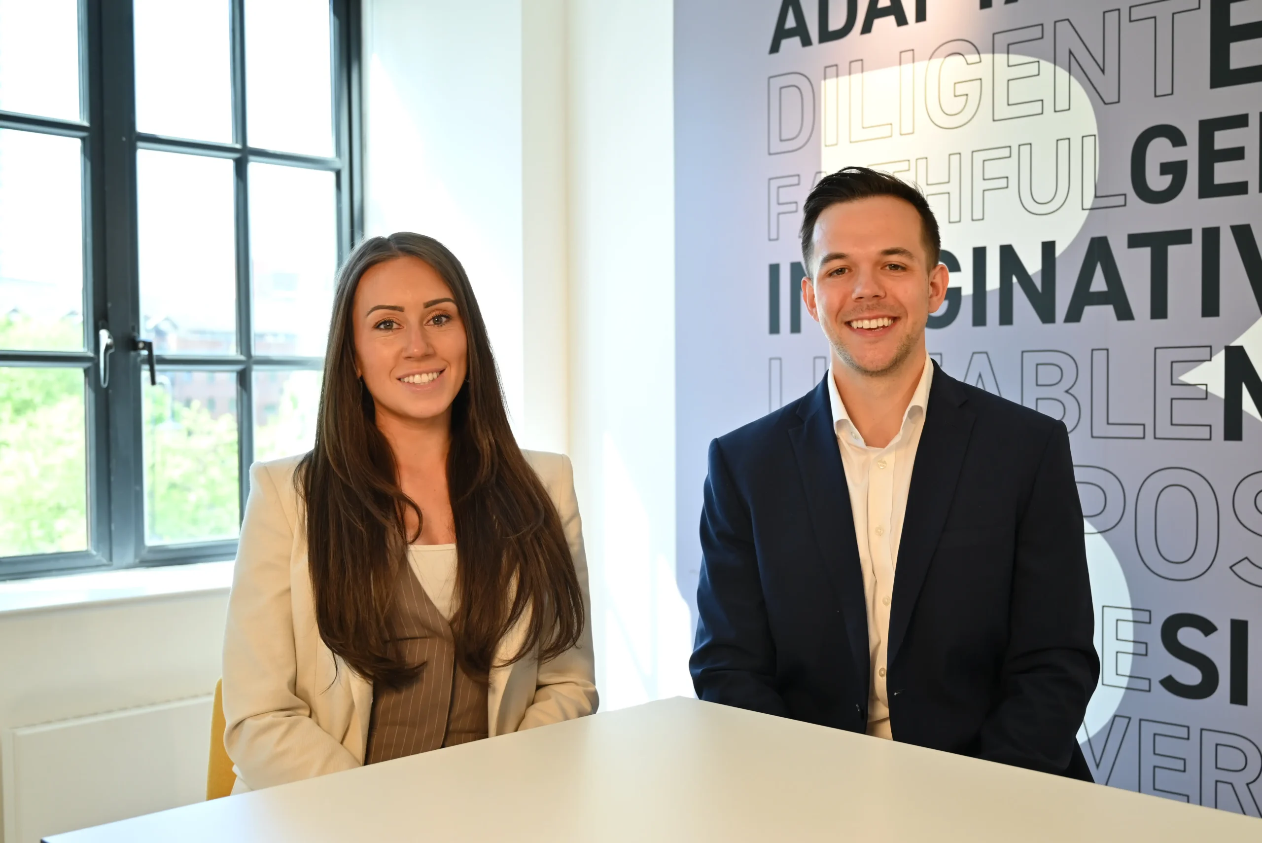 From left to right Lucy Cresswell and Russell Kaminski sit at a table looking at the camera.