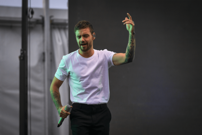 Liam Payne singing on stage with a microphone.