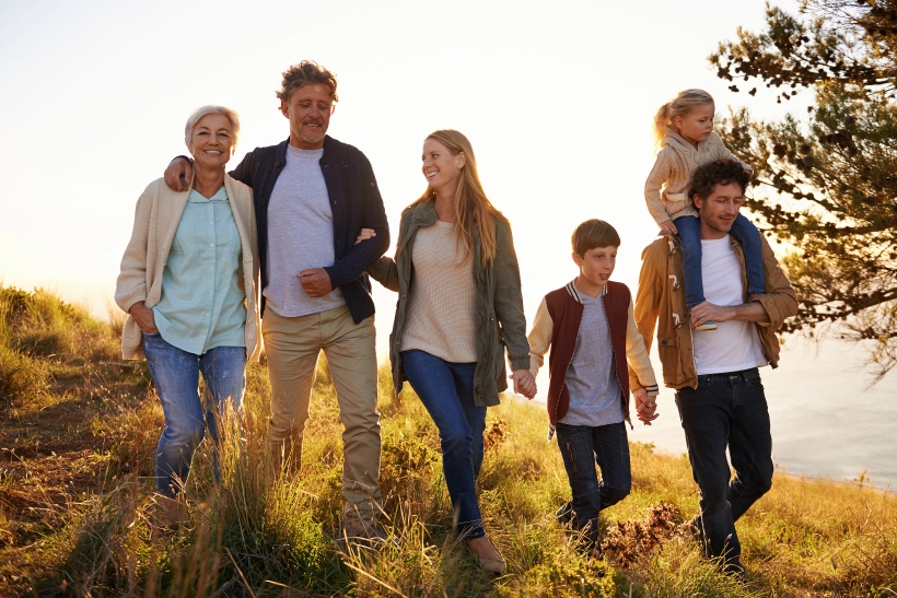 Six members of a family at various ages taking a walk on a sunny hill